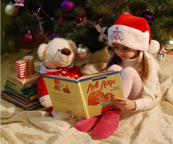 girl reading under Christmas tree